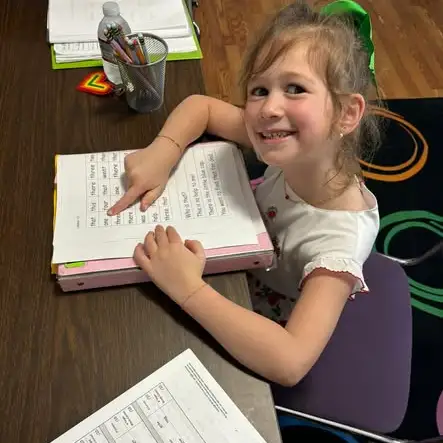 A student smiles while writing in her notebook