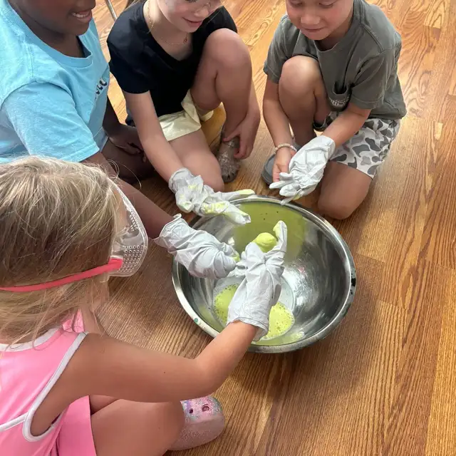 Students gathered around a hands on science experiment